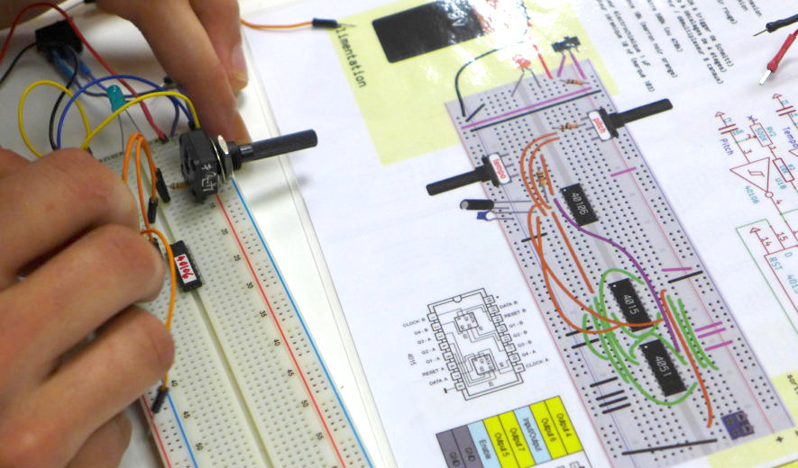 une personne fabrique un circuit électronique musical
